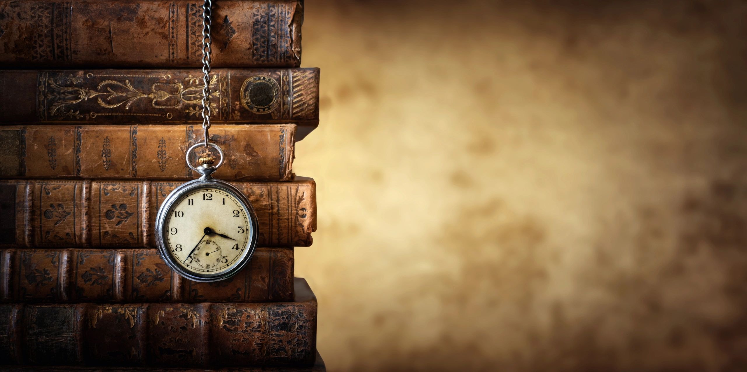 Antique pocket watch resting on old leather-bound books